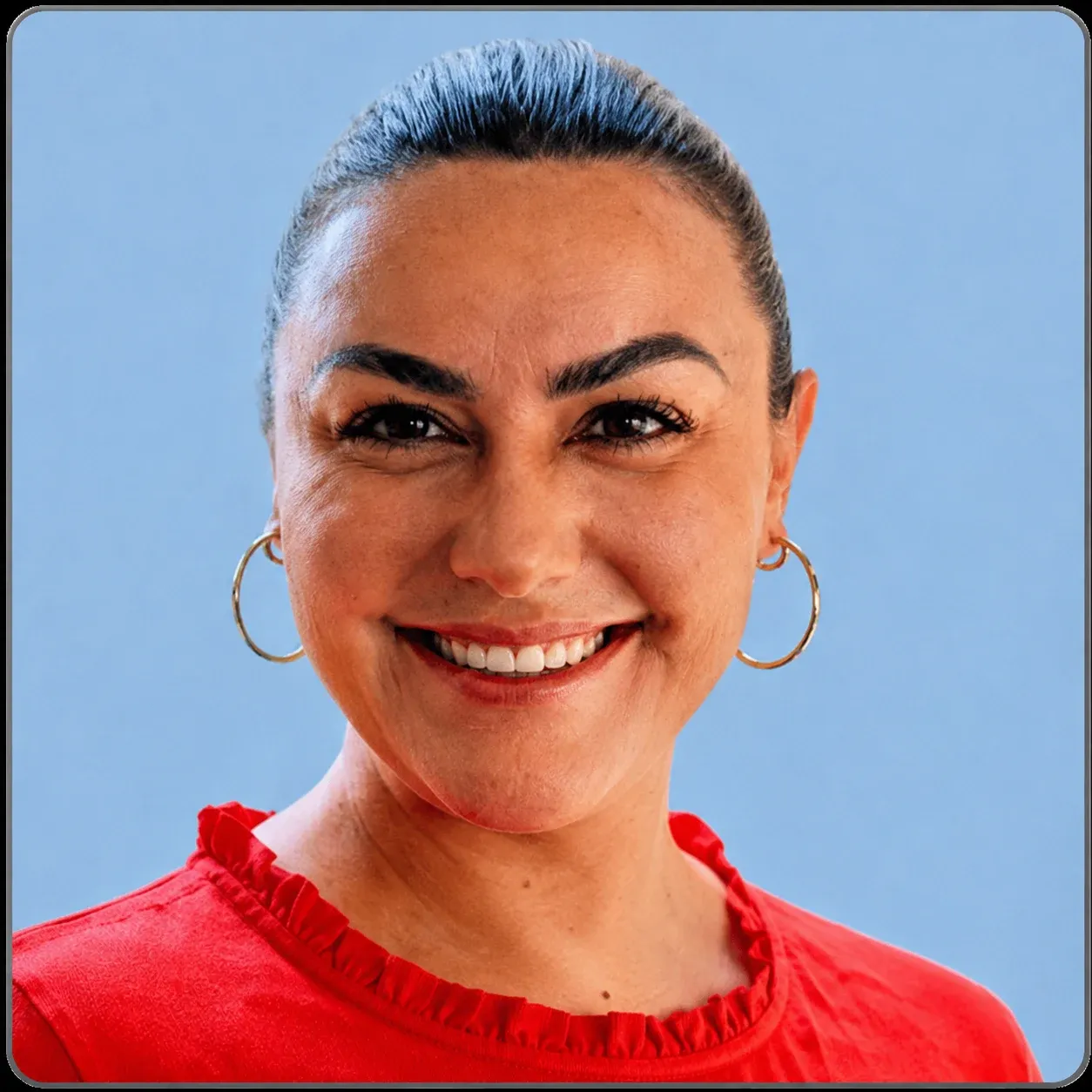 Smiling woman with dark hair, gold hoop earrings, and a red top against a blue background.